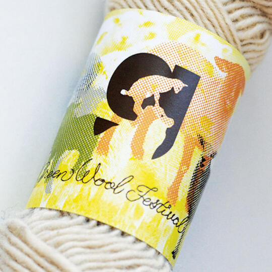 yarn with label with logo of "g" with lamb standing on sheep's head and "Green Wool Festival" with background sheep