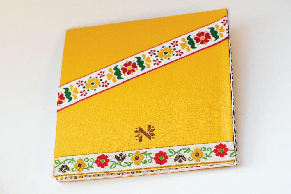 back of book, with "N" logo and ribbons over yellow fabric background