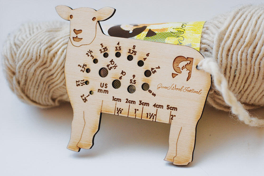 laser cut wood sheep with holes labeled with needle sizes, in front of yarn