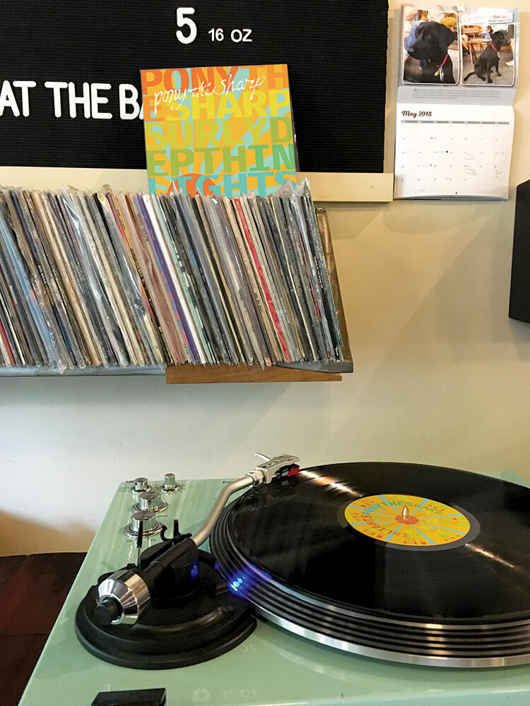 record on a turntable with album cover behind